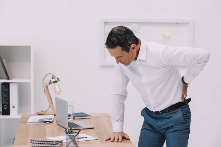 גבר סובל מכאב גב חמור כתוצאה מעבודה במשרד